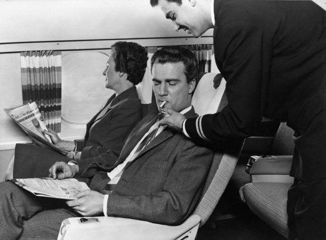 Personal de vuelo de KLM enciende un cigarrillo a un viajero, cuando la aerolínea permitía fumar.