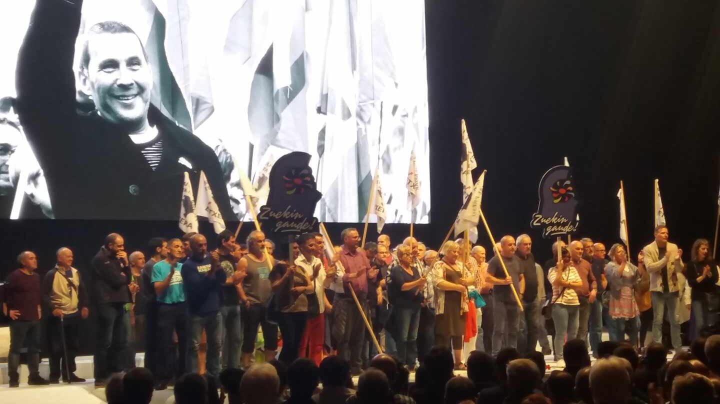 Presos de ETA son aplaudidos en el escenario del Bilbao Arena durante el acto de Sortu sobre una imagen de Arnaldo Otegi.