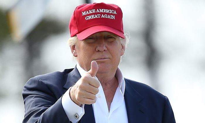 Donald Trump con su conocida gorra roja de "Make America Great Again", enseñando el dedo pulgar