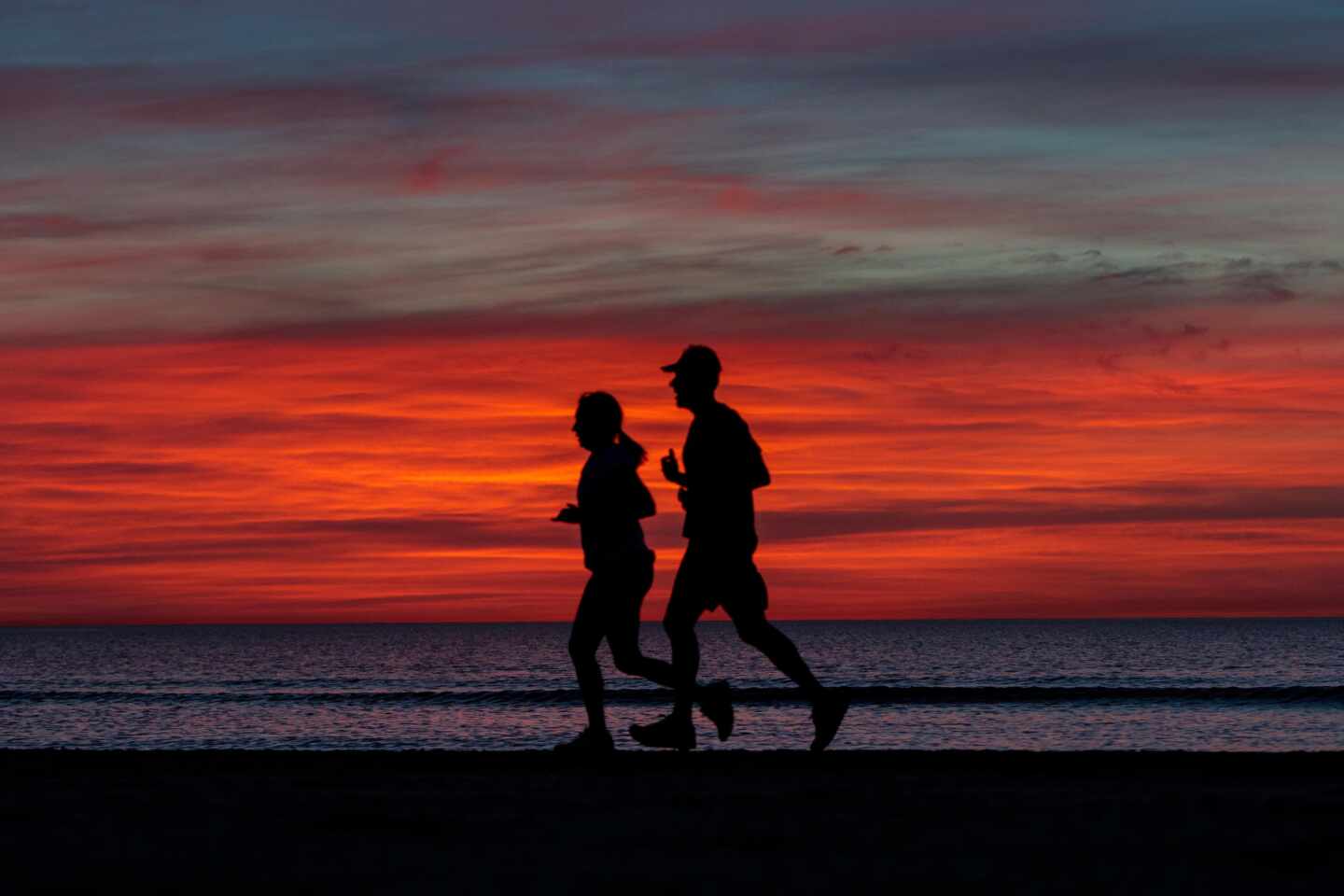Dos personas practican deporte en la playa de la malvarrosa de Valencia a primera hora de la mañana.