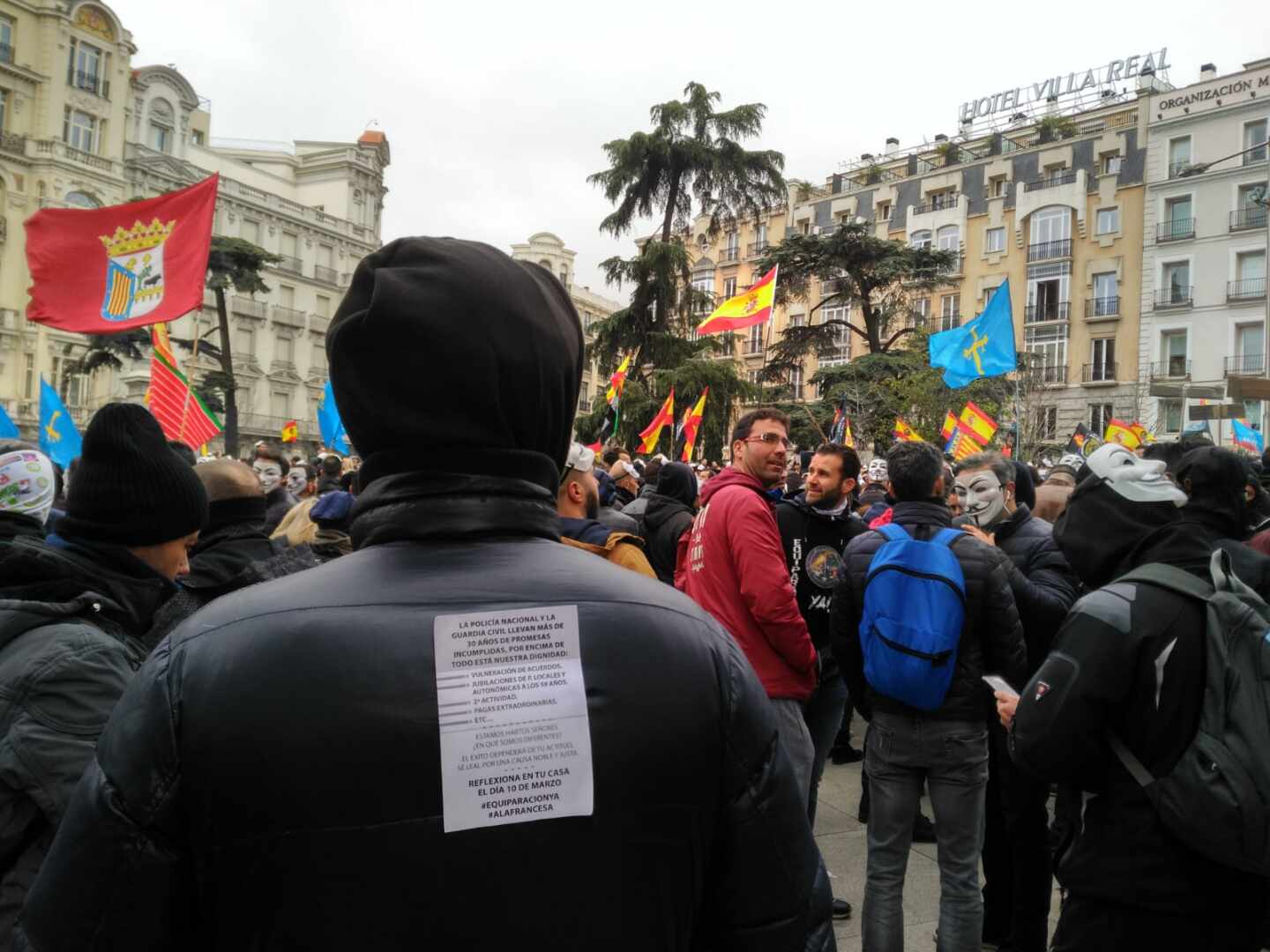 Un manifestante en la concentración convocada por Jusapol, con la octavilla que llama a 'reflexionar en casa' el 10 de marzo.