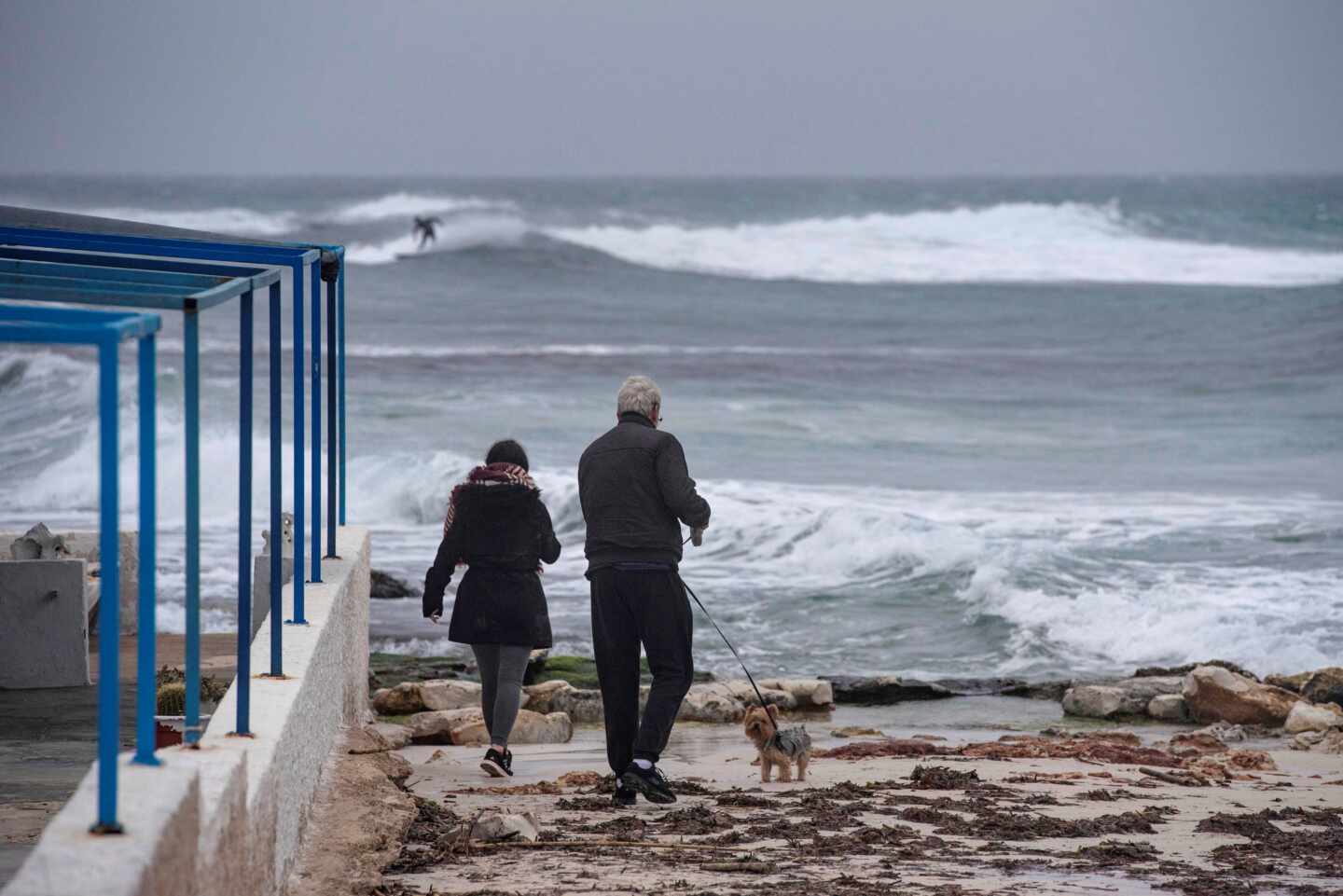 Dos personas caminan a la orilla de la costa de Biniancolla, en la isla de Menorca.