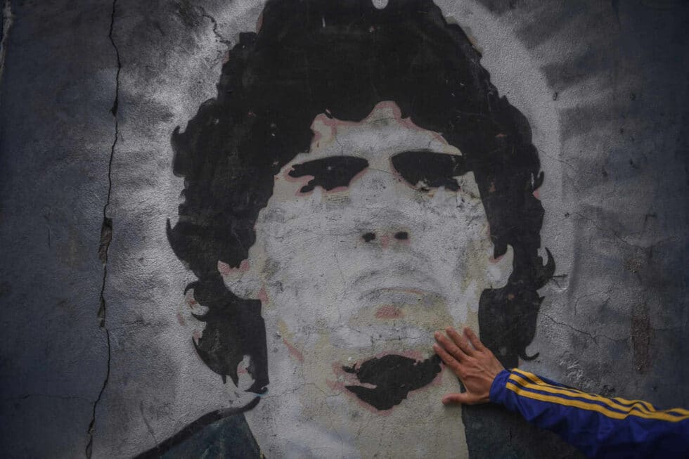 Un fan de Boca Juniors toca un mural de Diego Armando Maradona.