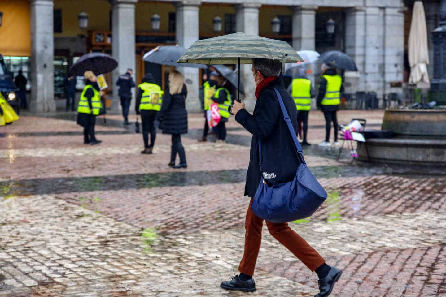 Una mujer camina protegida por un paraguas en la Plaza Mayor de Madrid.