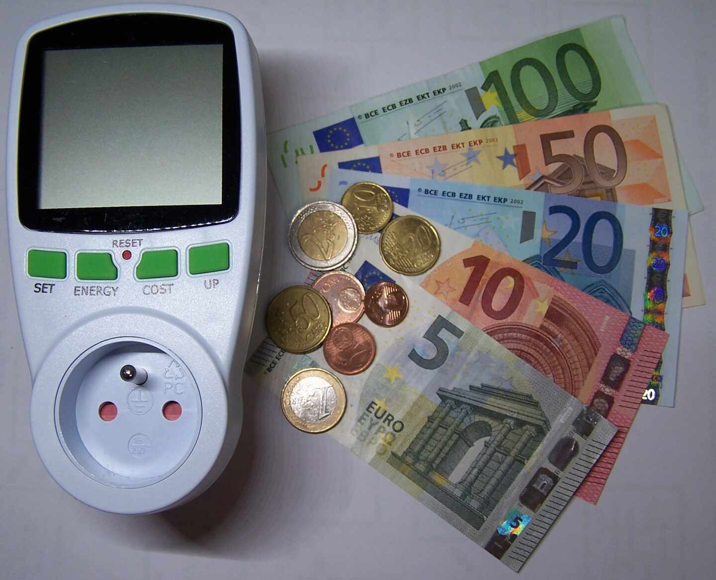 Imagen de un potenciador de luz junto a varios billetes de euros y algunas monedas