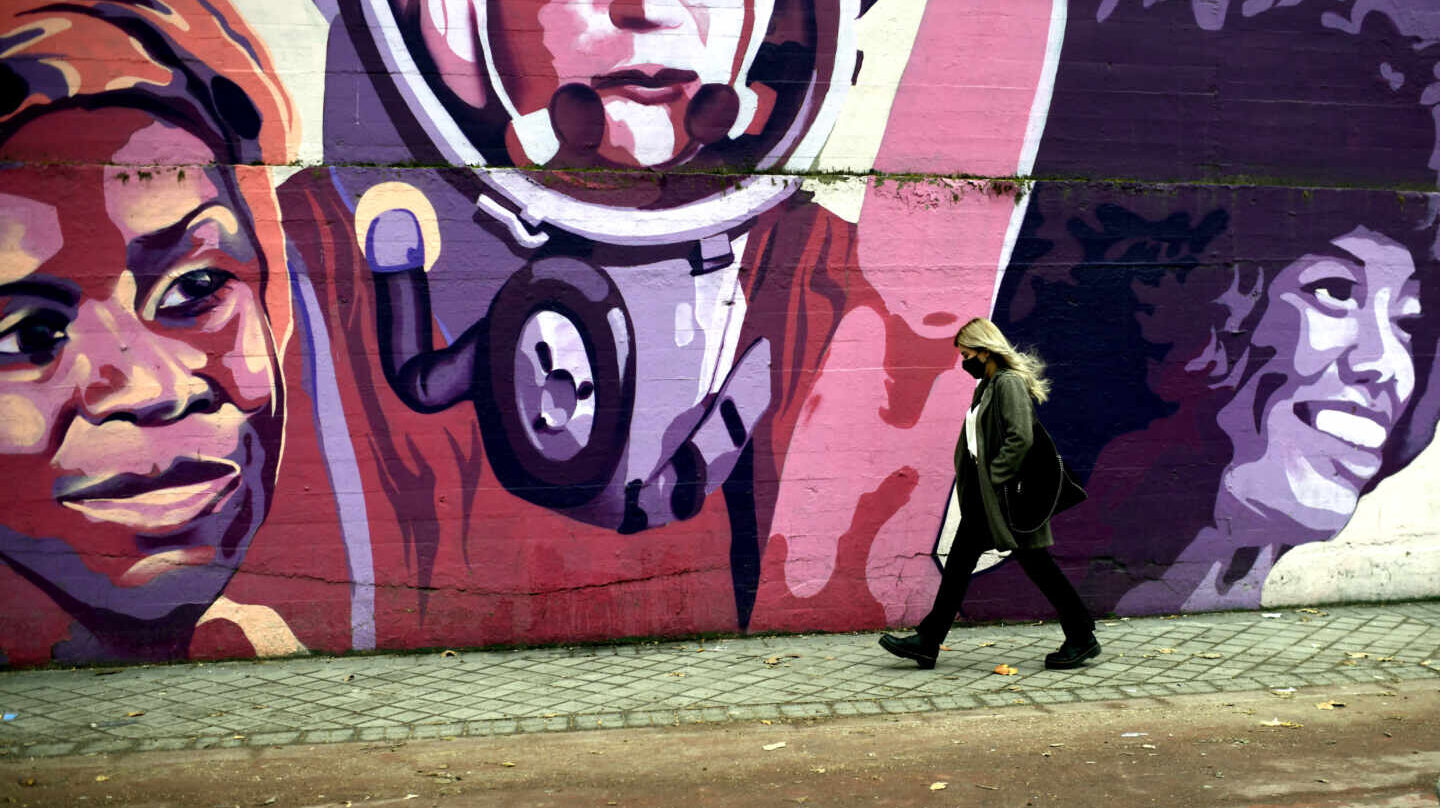 Una mujer pasa por el mural feminista en el polideportivo municipal de la Concepción en el distrito de Ciudad Lineal (Madrid).