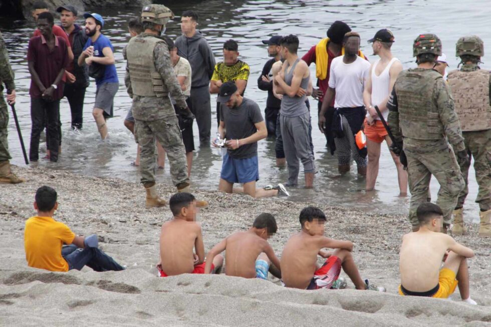 Miembros del Ejército de Tierra vigilan a un grupo de inmigrantes que han logrado cruzar uno de los espigones fronterizos de Ceuta