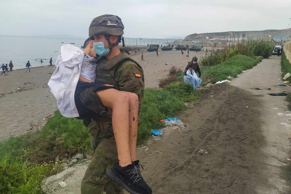 Un militar del Ejército ayuda a un inmigrante en uno de los espigones fronterizos de Ceuta