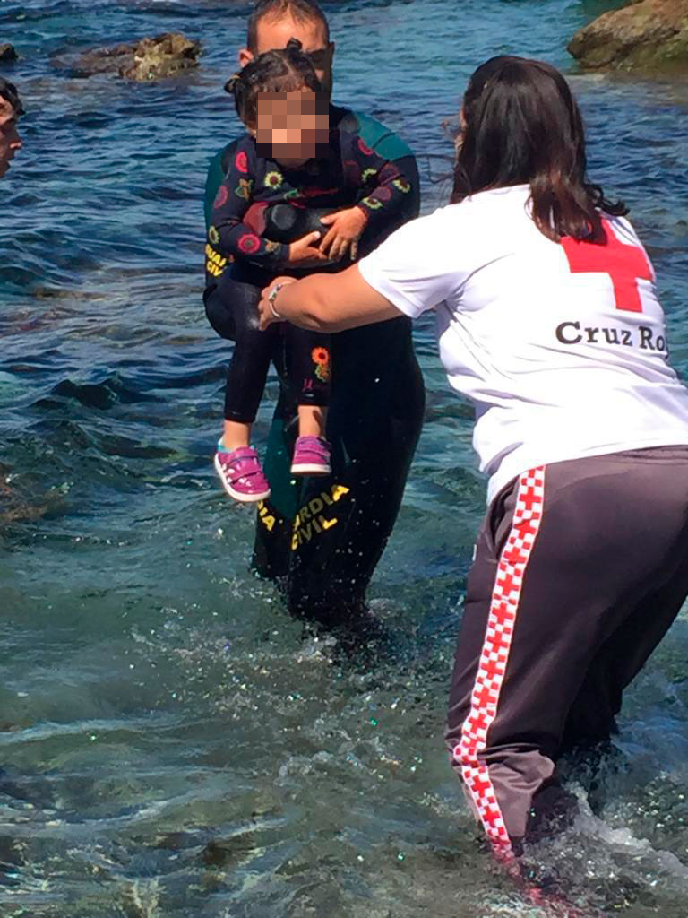 Un Guardia Civil y una miembro de Cruz de Roja ayudan a una niña en Ceuta tras sacarla del agua