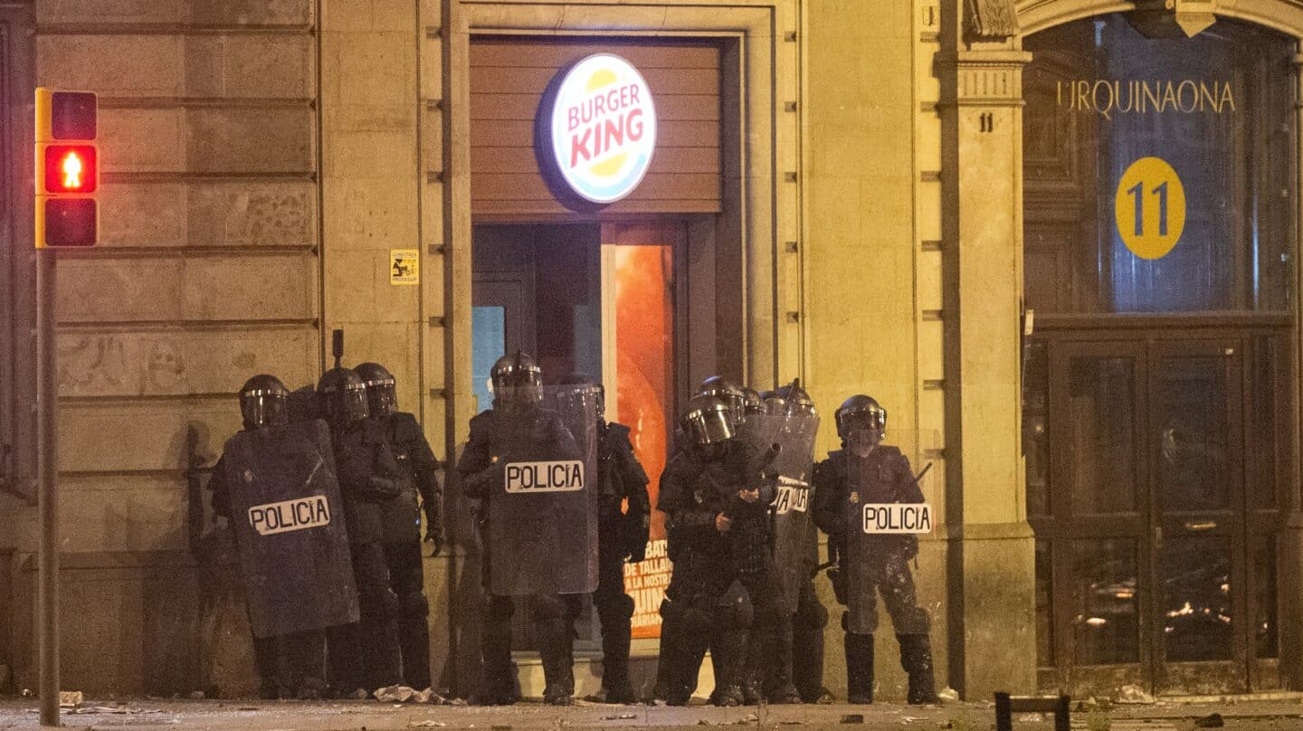 Agentes de la Policía Nacional, a las puertas de un establecimiento comercial durante los disturbios registrados en la barcelonesa Plaza de Urquinaona el 18 de octubre de 2019.
