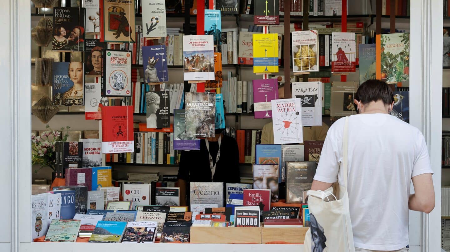 Un hombre se interesa por un libro en la Feria del Libro de Madrid.