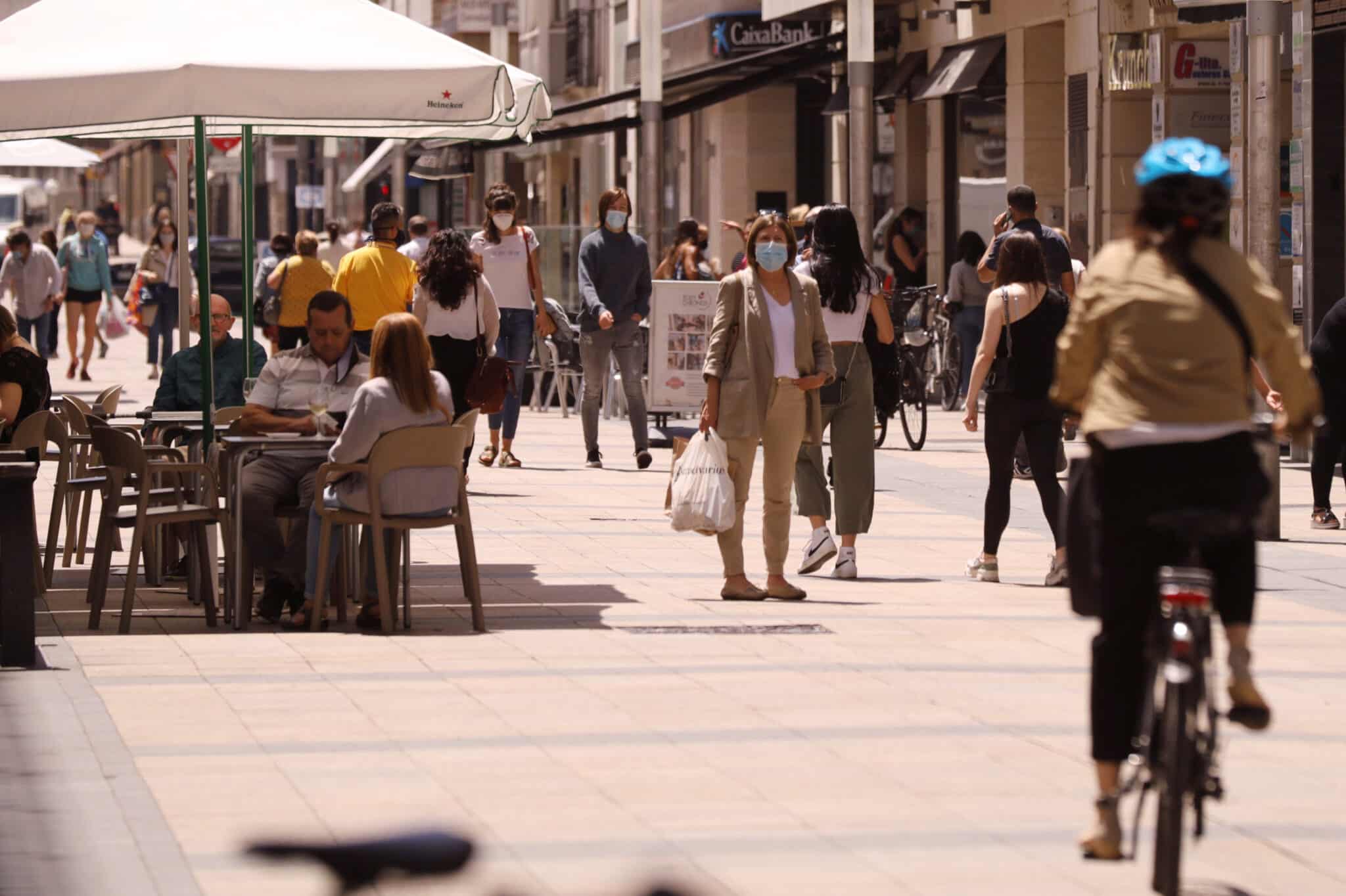 Personas paseando con mascarillas y sentadas en terrazas en una céntrica calle de Vitoria