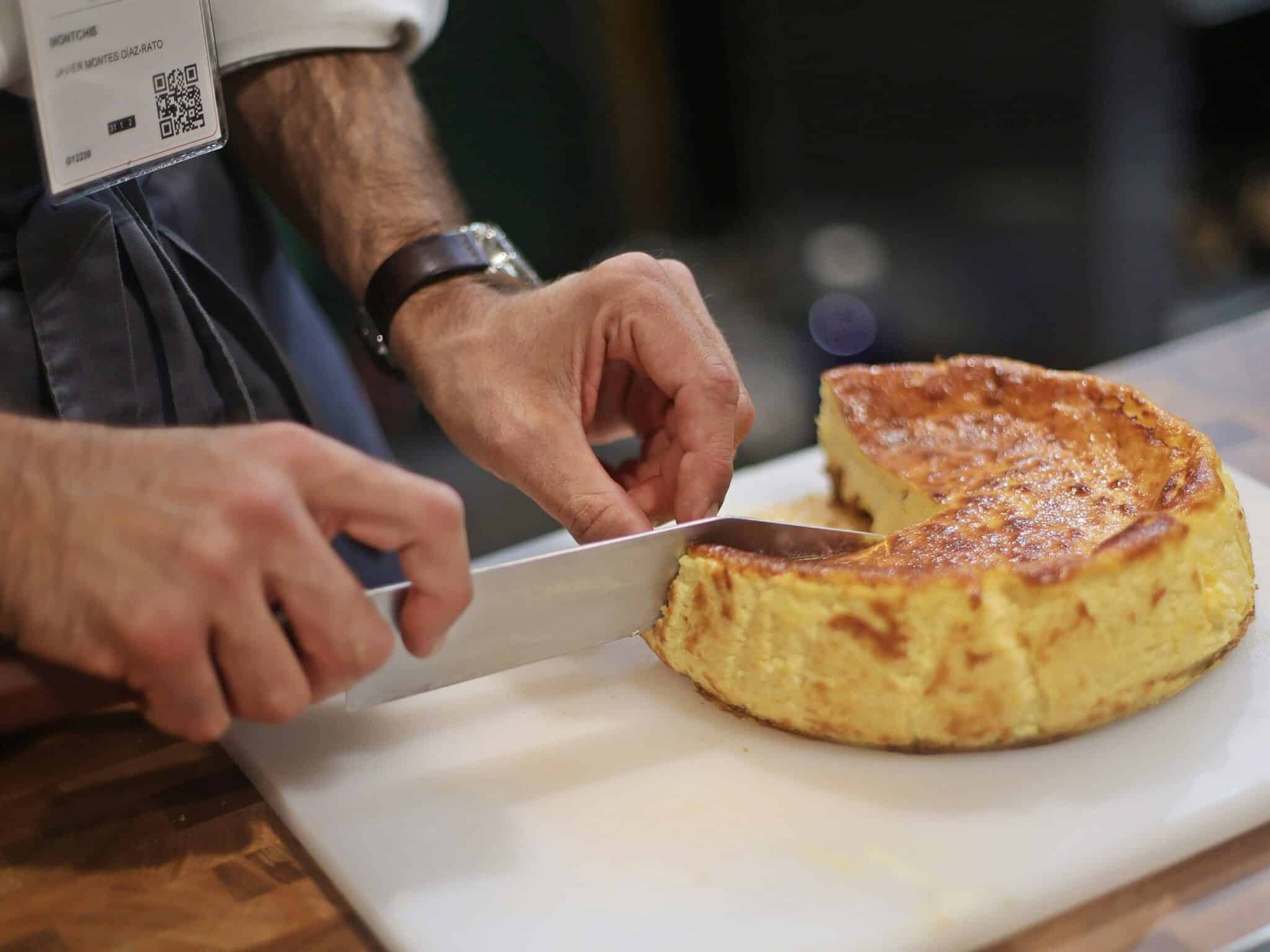 Un camarero corta una porción de tarta de queso en un stand de una feria de Madrid.