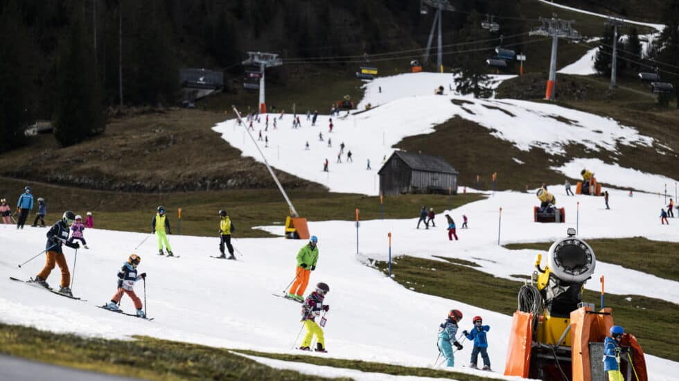 Skiers in the Swiss Alps glide down cannon-created ski slopes in the absence of snow.