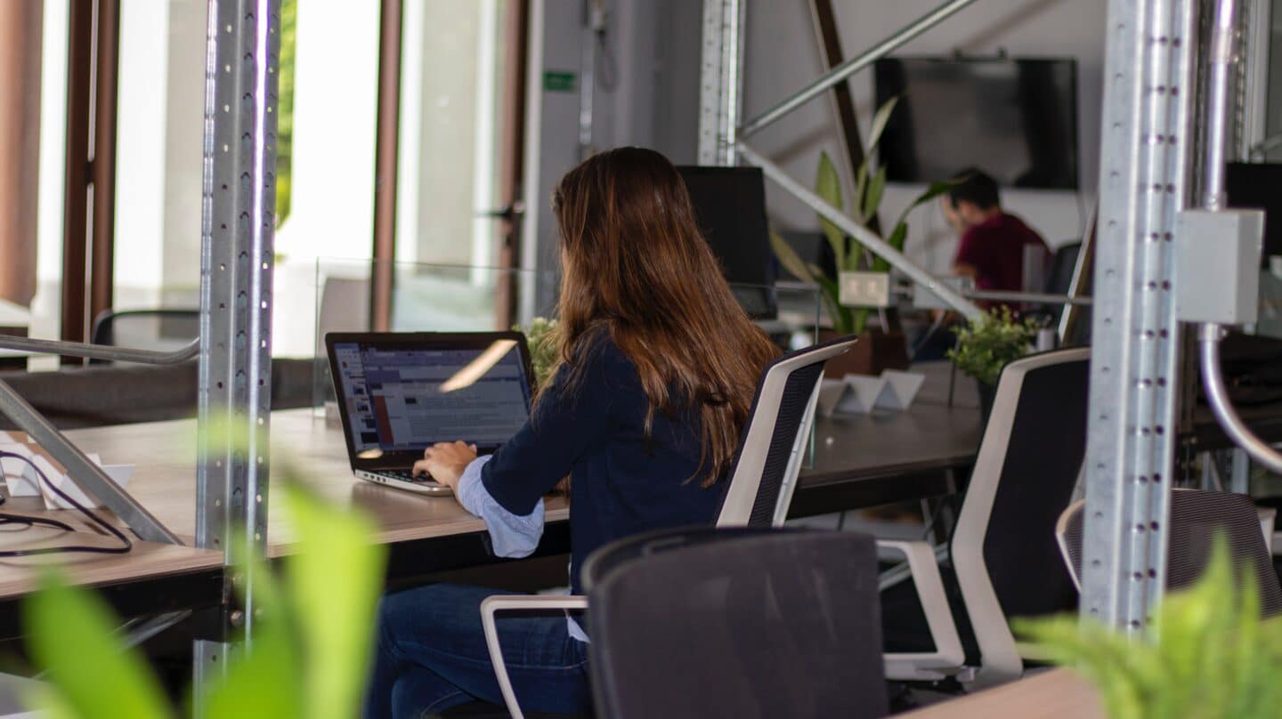 Una mujer trabaja frente a un ordenador en una oficina.