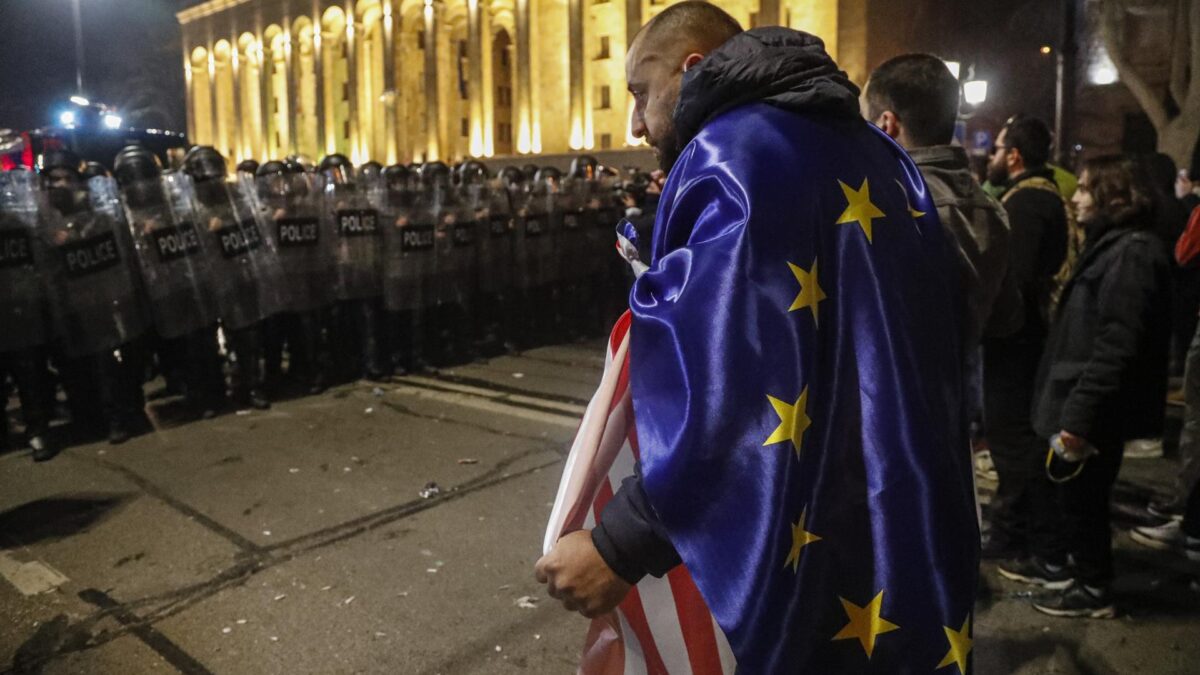 Un manifestante, con banderas de la Unión Europea y Estados Unidos, frente a los antidisturbios en Tbilisi.