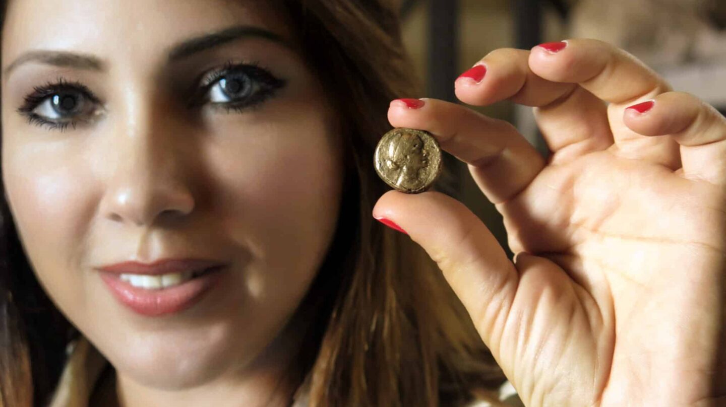 La arqueóloga Kathleen Martínez muestra una de las monedas con rostro de Cleopatra hallada en Taposiris Magna.