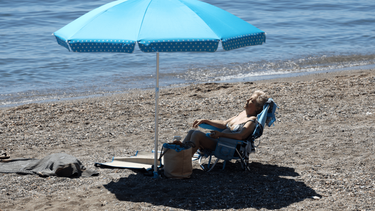 El tiempo en España marcado por el calor extremo en el fin de semana de junio 2023, con una señora tomando el sol en una playa de Málaga