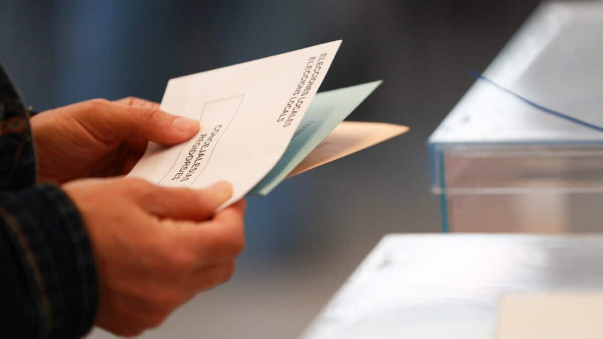 Una persona sostiene papeletas electorales frente a las urnas, a 28 de mayo de 2023,