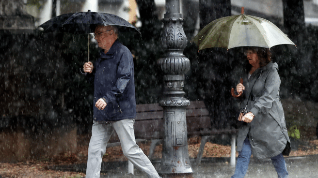 Two people protect themselves from the rain with umbrellas, and Jorge Rey once again contradicts Aemet's forecasts for the fall of 2023.
