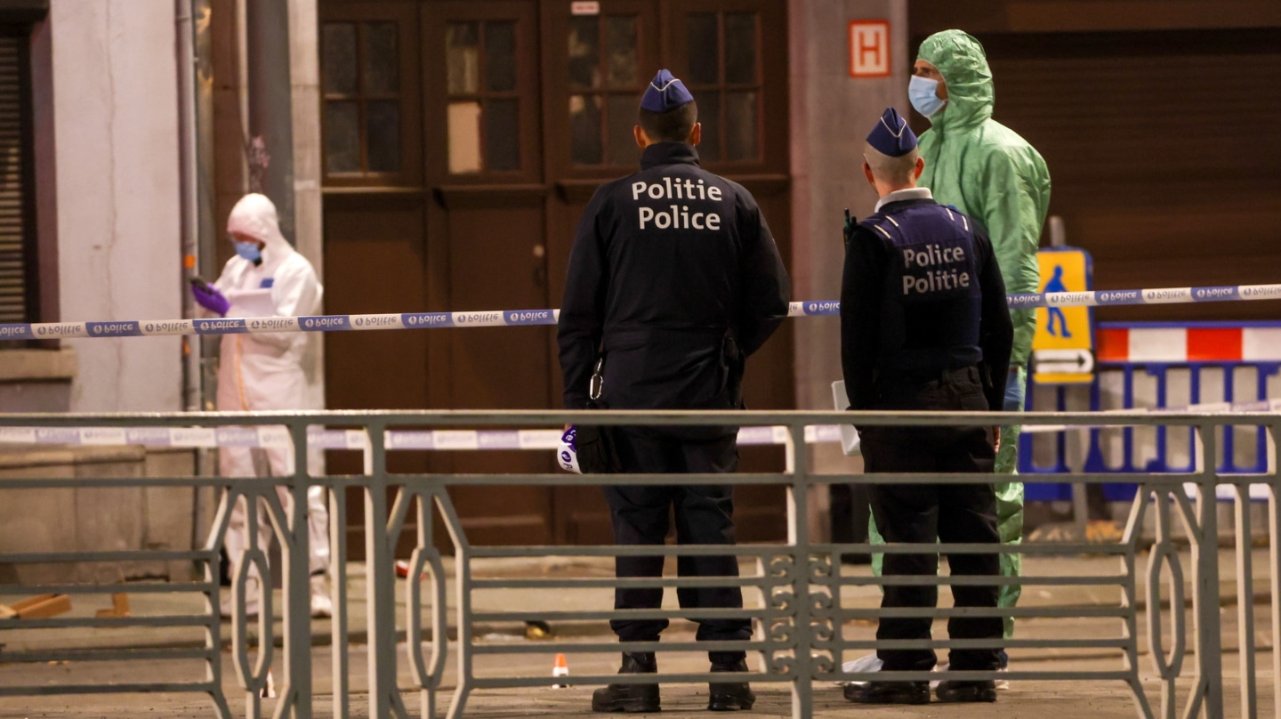 Agentes de policía y forenses belgas trabajan detrás de un cordón en el lugar de un tiroteo en Bruselas, Bélgica