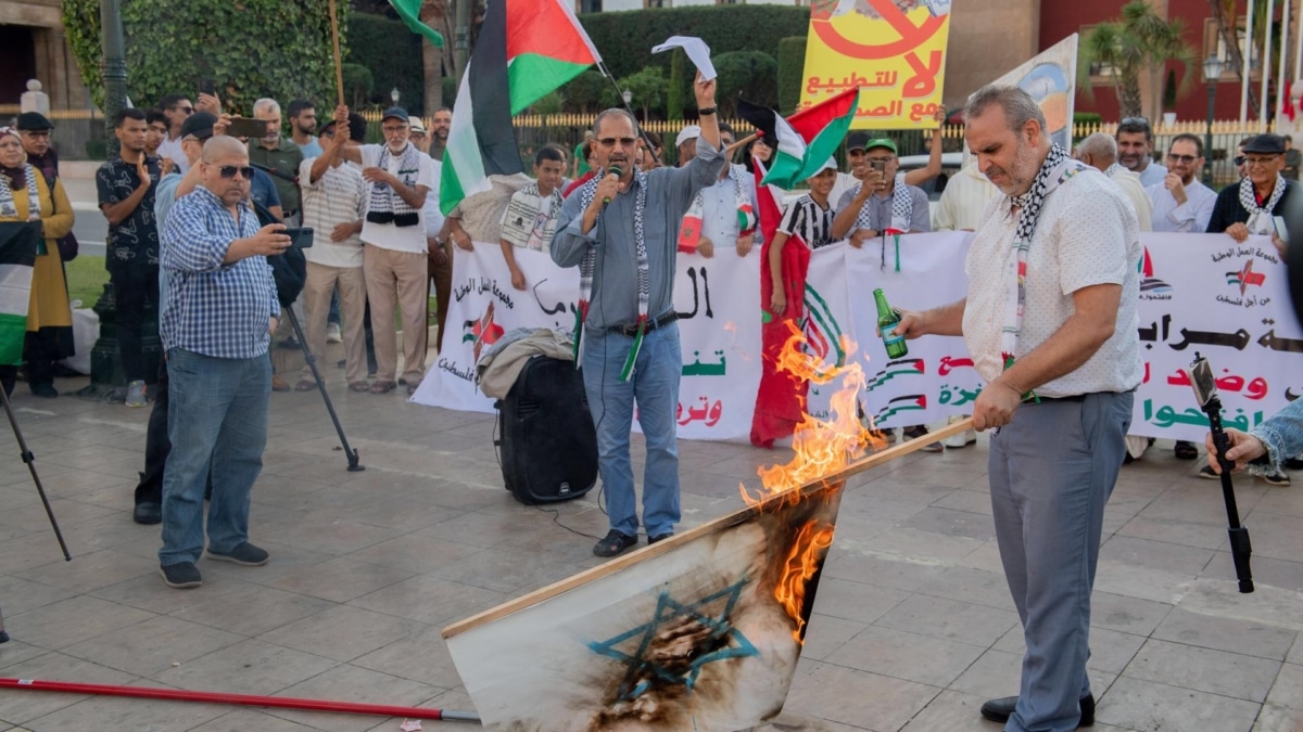 Un hombre quema una bandera israelí en una protesta en solidaridad con Palestina en Rabat.