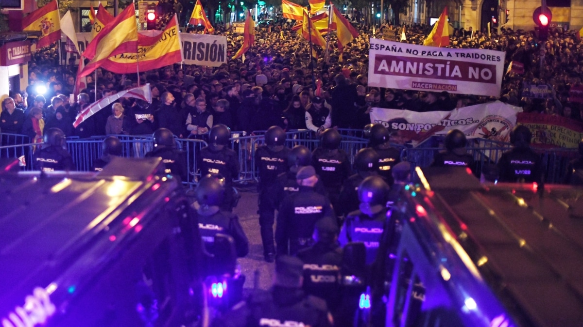 Decenas de personas con banderas y pancartas durante una concentración en contra de la amnistía, frente a la sede del PSOE en la calle Ferraz