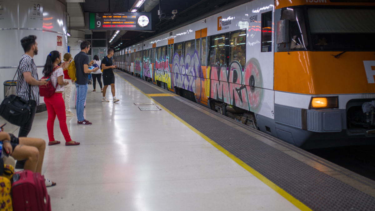 Viajeros esperan la llegada de un tren en uno de los andenes de la estación de Sants.