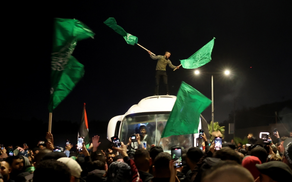 Un partidario de Hamás celebra en lo alto de un autobús que transportaba prisioneros palestinos liberados