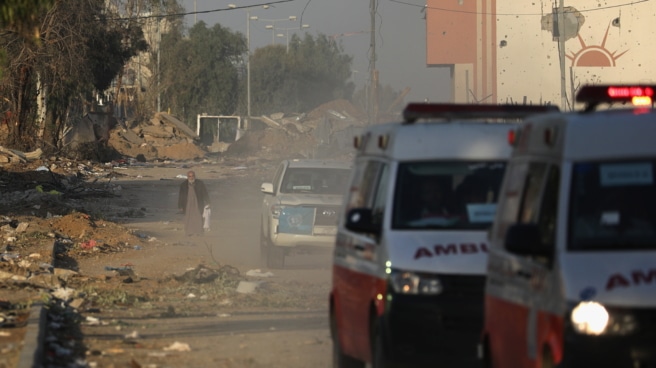 An elderly Palestinian man walks behind Palestinian ambulances carrying the wounded.