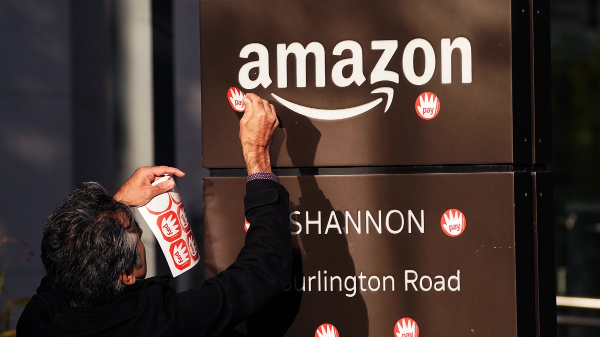 Una persona pega pegatinas con el lema "pay" en la sede de Amazon en Irlanda.