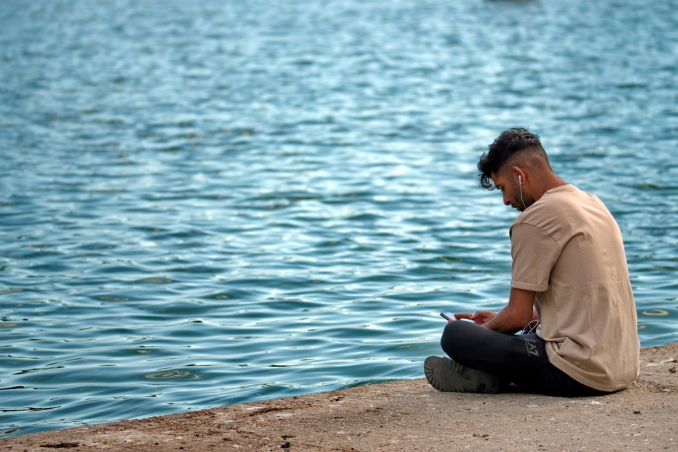 Una imagen de un hombre escuchando música frente al mar. 