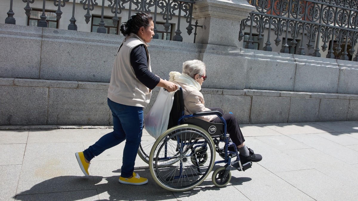 Una mujer mayor en silla de ruedas y su cuidadora pasean por el centro de Madrid, en una imagen de archivo.