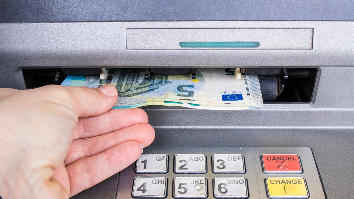 Pensionista sacando el dinero de su paga extra de verano 2024 en un cajero de un banco