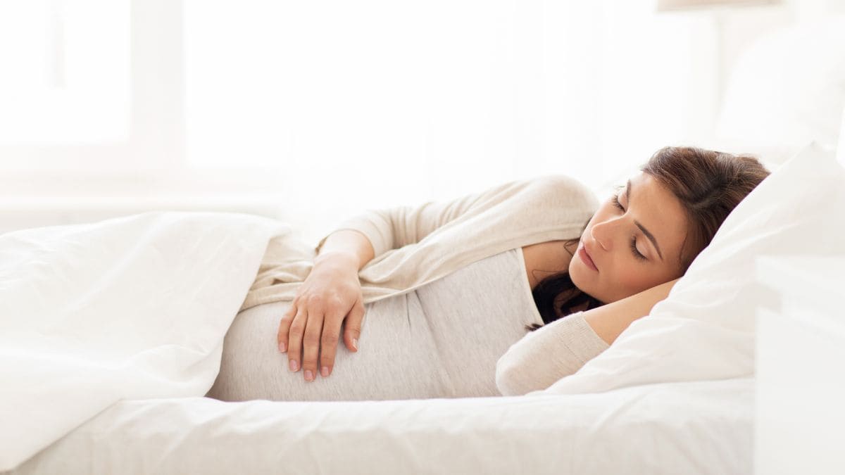Mujer embarazada que busca la mejor postura para dormir