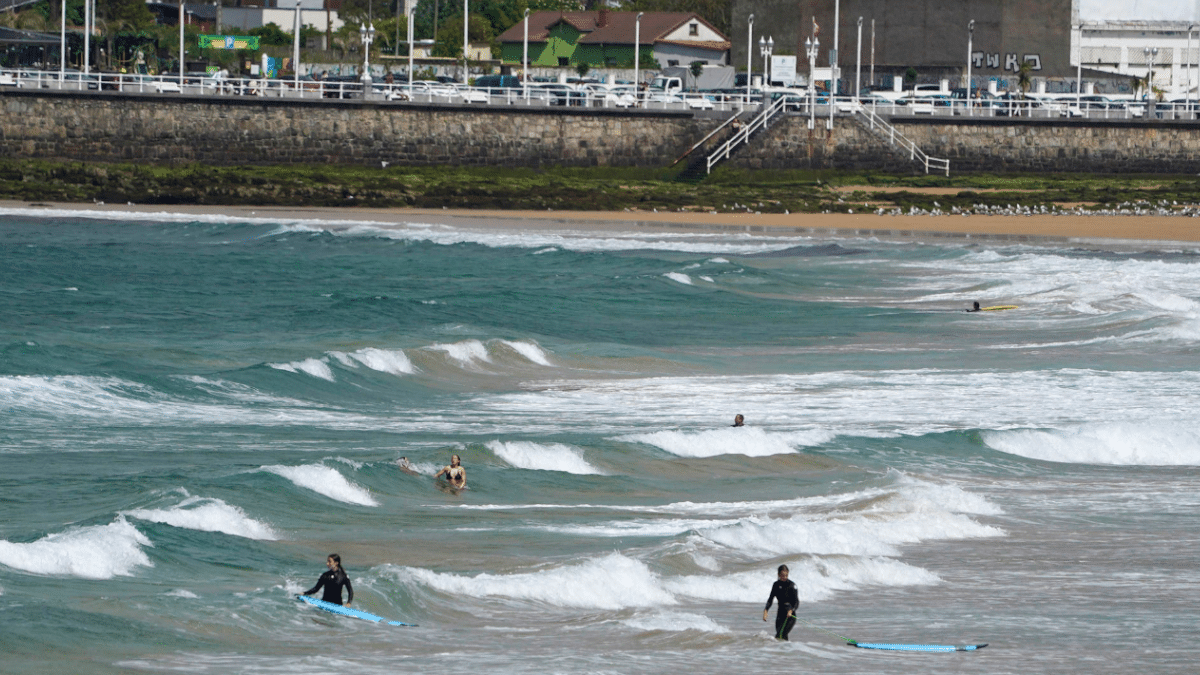 Surfistas y bañistas disfrutan de las olas este viernes en la playa de San Lorenzo de Gijón.