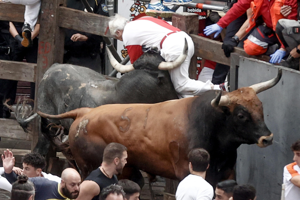 Un mozo es embestido por uno de los toros de la ganadería sevillana de Miura durante el último encierro de los Sanfermines 2024, este domingo, en Pamplona. 
