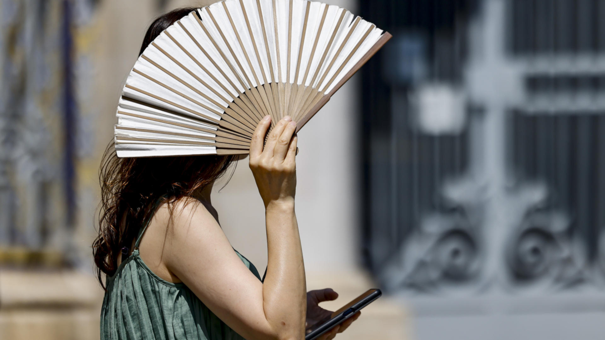 Una mujer se protege del intenso calor con un abanico en València.