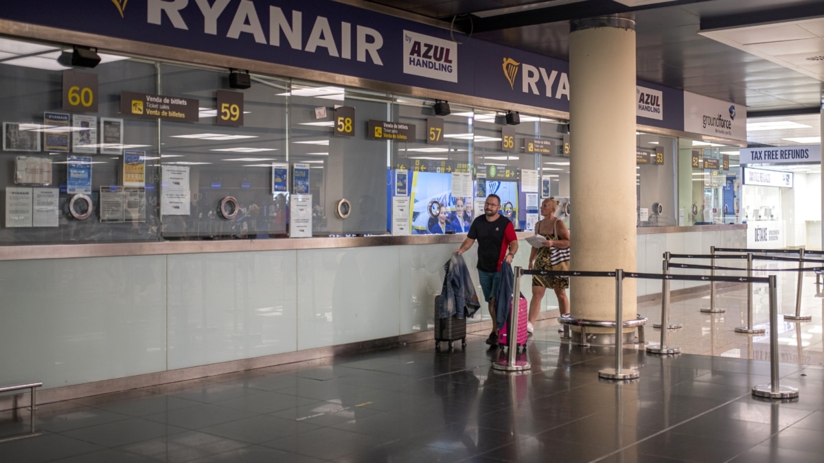 Dos personas pasan junto a una ventanilla de Ryanair en el Aeropuerto Josep Tarradellas Barcelona-El Prat