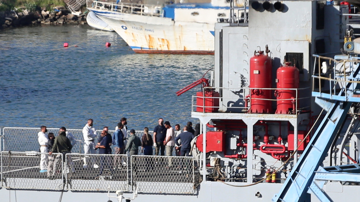 Un grupo de migrantes interceptados en aguas italianas llegan a bordo de un barco de la marina italiana