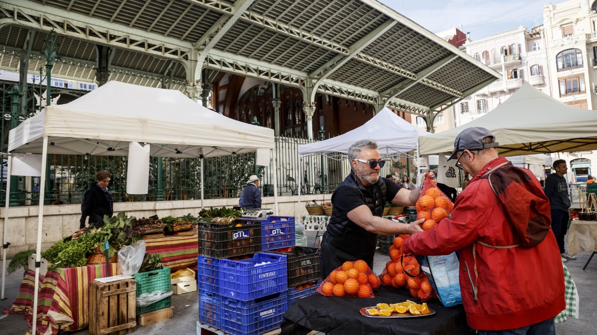 Un hombre compra naranjas en un puesto del nuevo mercado de la huerta del Pla del Remei, en el Mercado de Colón de Valencia