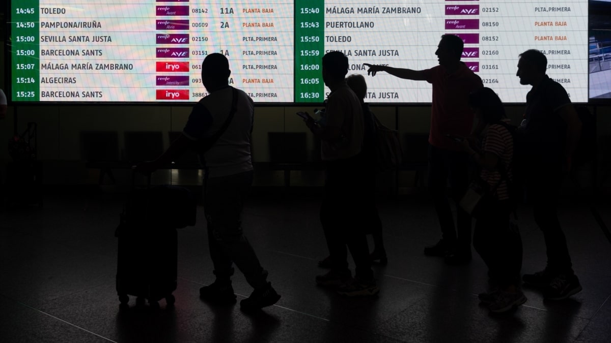 Varias personas esperando trenes en Atocha