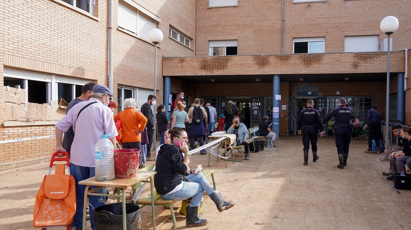 Varias personas hacen cola para conseguir alimentos en el instituto público de Sedaví, Valencia.