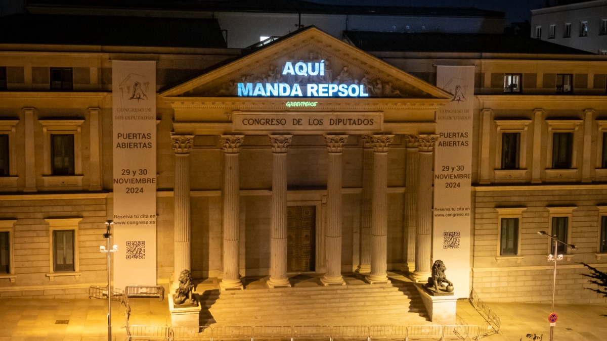 Greenpeace proyecta sobre el edificio del Congreso de los Diputados el mensaje “Aquí manda Repsol” para denunciar la retirada del impuesto a las energéticas.