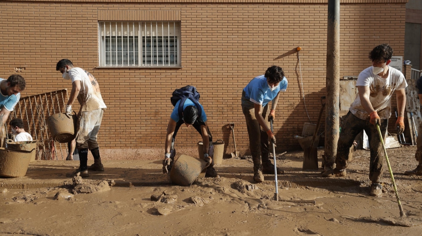 Varios jóvenes trabajan para despejar una calle de Paiporta en los primeros días tras la DANA que asoló Valencia.