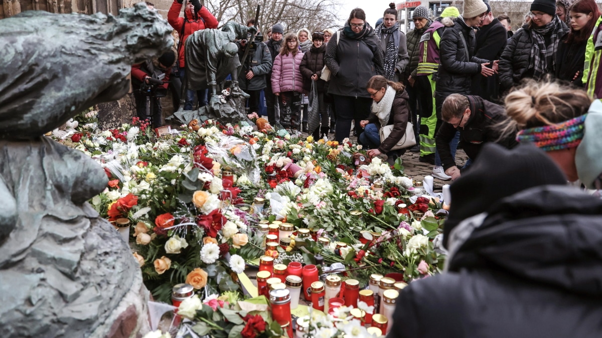 Varias personas depositan flores y encienden velas en el lugar oficial de luto tras el ataque en el mercado navideño en Magdeburgo (Alemania).