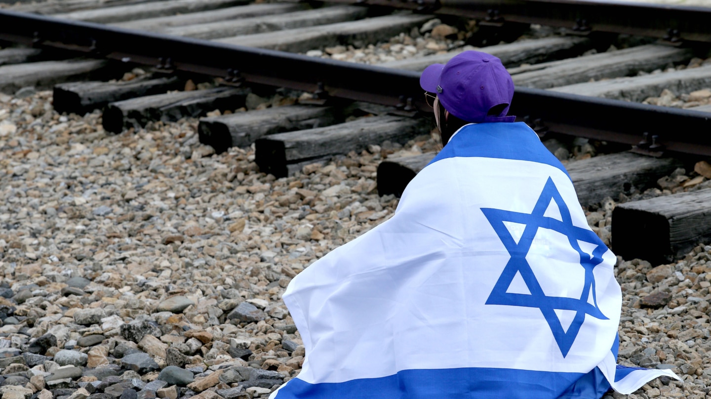 Una chica con una bandera isralí en el campo de concentración de Auschwitz, en Polonia