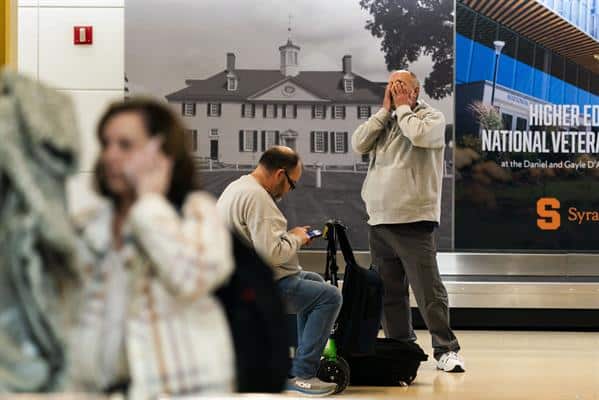 Varias personas esperan en el aeropuerto Ronald Reagan de Washington después de la colisión entre un avión de pasajeros y un helicóptero militar.