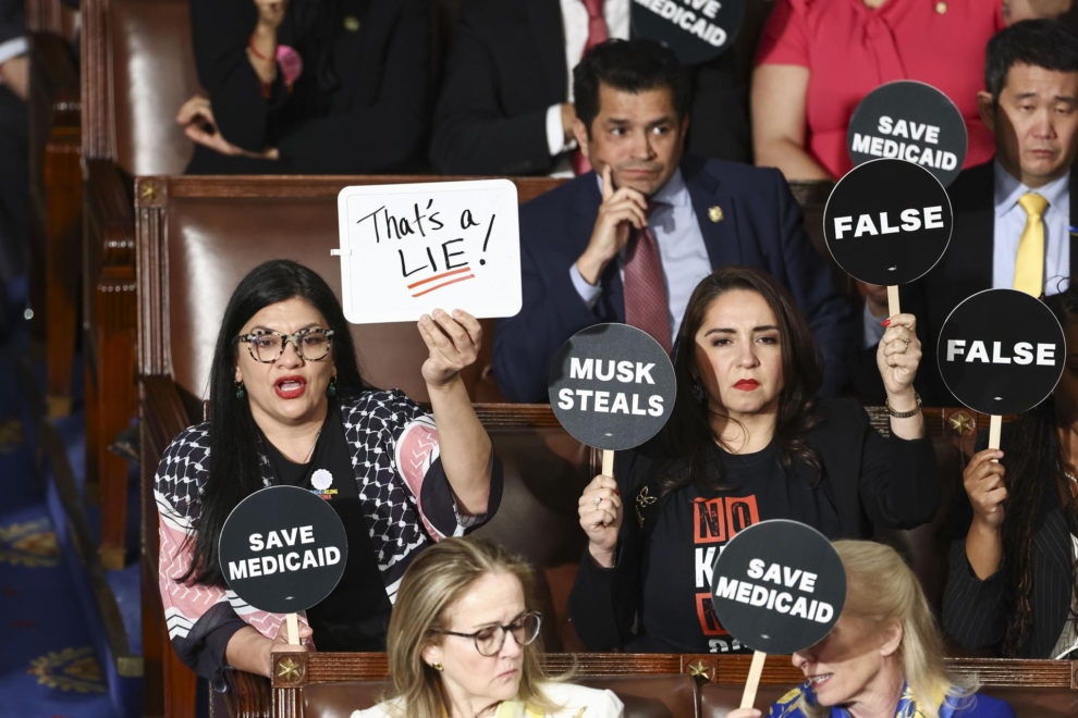 Representantes demócratas sostienen carteles durante el primer discurso de Trump ante la Cámara.