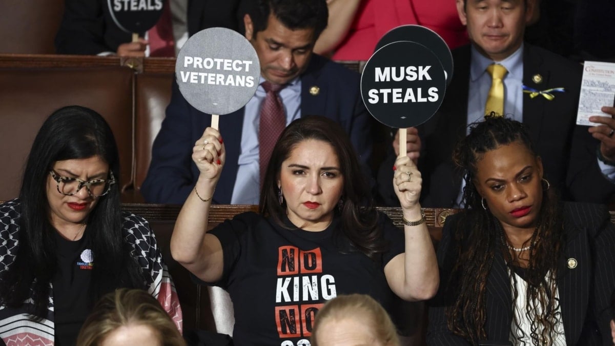 La congresista por Illinois Delia Ramírez (en el centro) y otras representantes demócratas sostienen carteles de protesta contra Trump durante el discurso presidencial del pasado martes en el Capitolio.